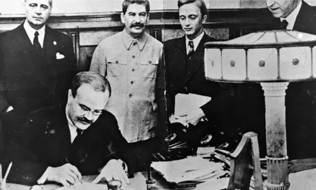 Molotov signs the non-aggression pact in the presence of Ribbentrop (left) and Stalin.